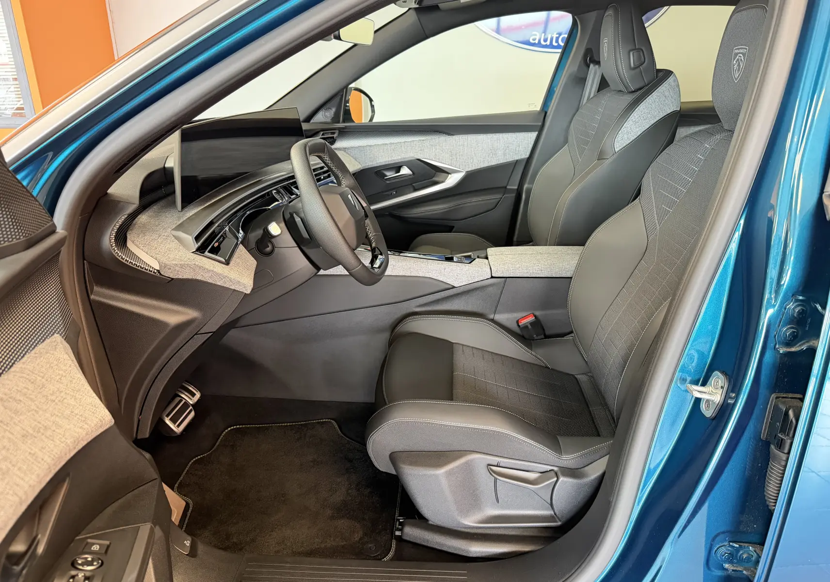 Vue intérieure côté conducteur du Peugeot 3008 Hybrid 145 GT bleu obsession, avec sellerie tissu embossée et tableau de bord moderne.