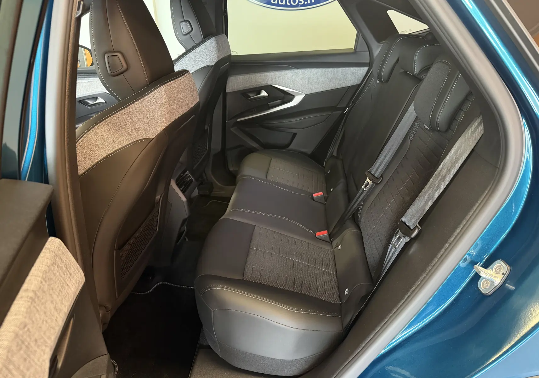 Vue intérieure arrière droite du Peugeot 3008 Hybrid 145 GT bleu obsession, sièges tissu noir et gris avec surpiqûres claires.