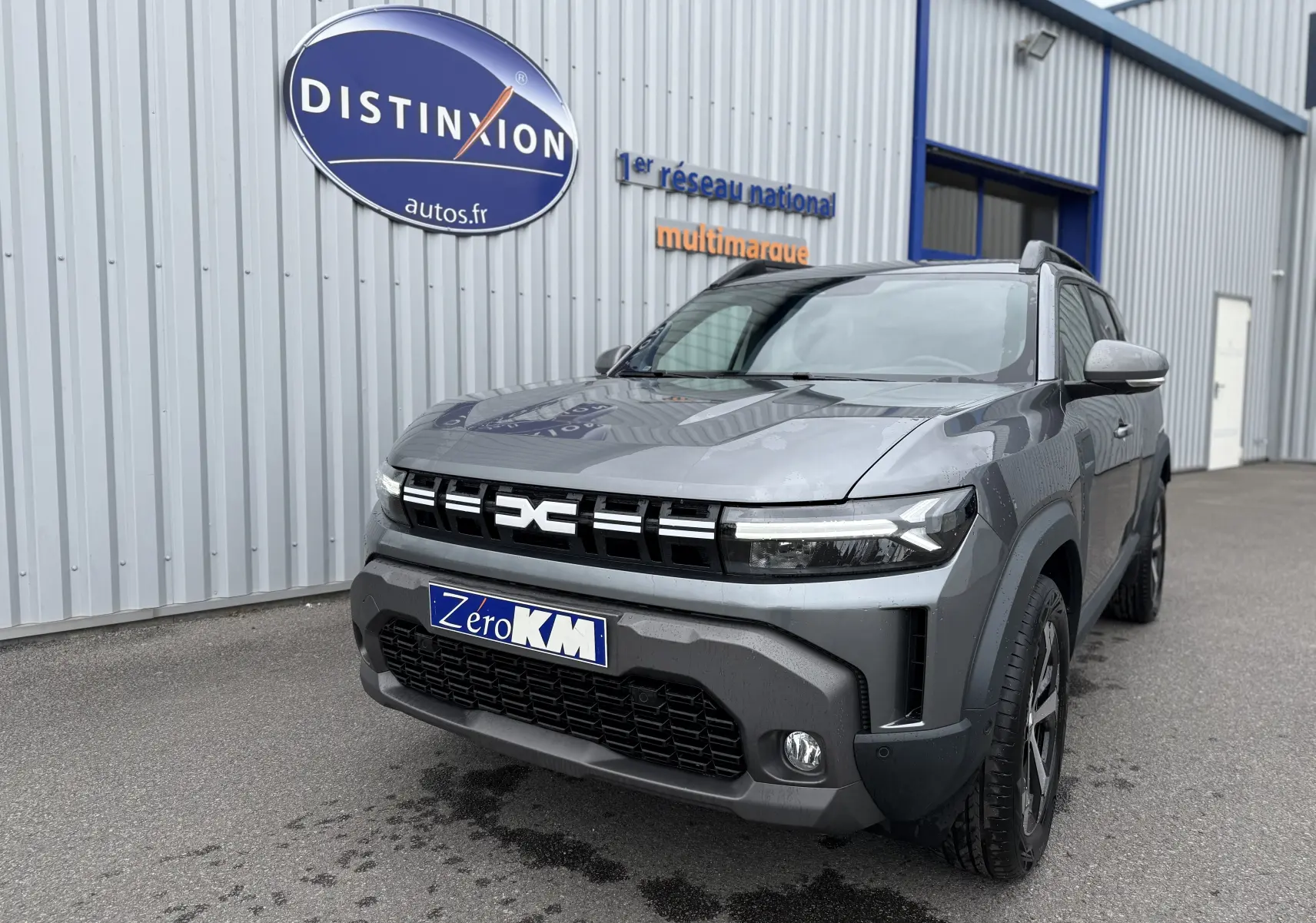 Dacia Duster 2025 gris schiste en 3/4 avant droit, avec calandre distinctive et phares LED modernes.