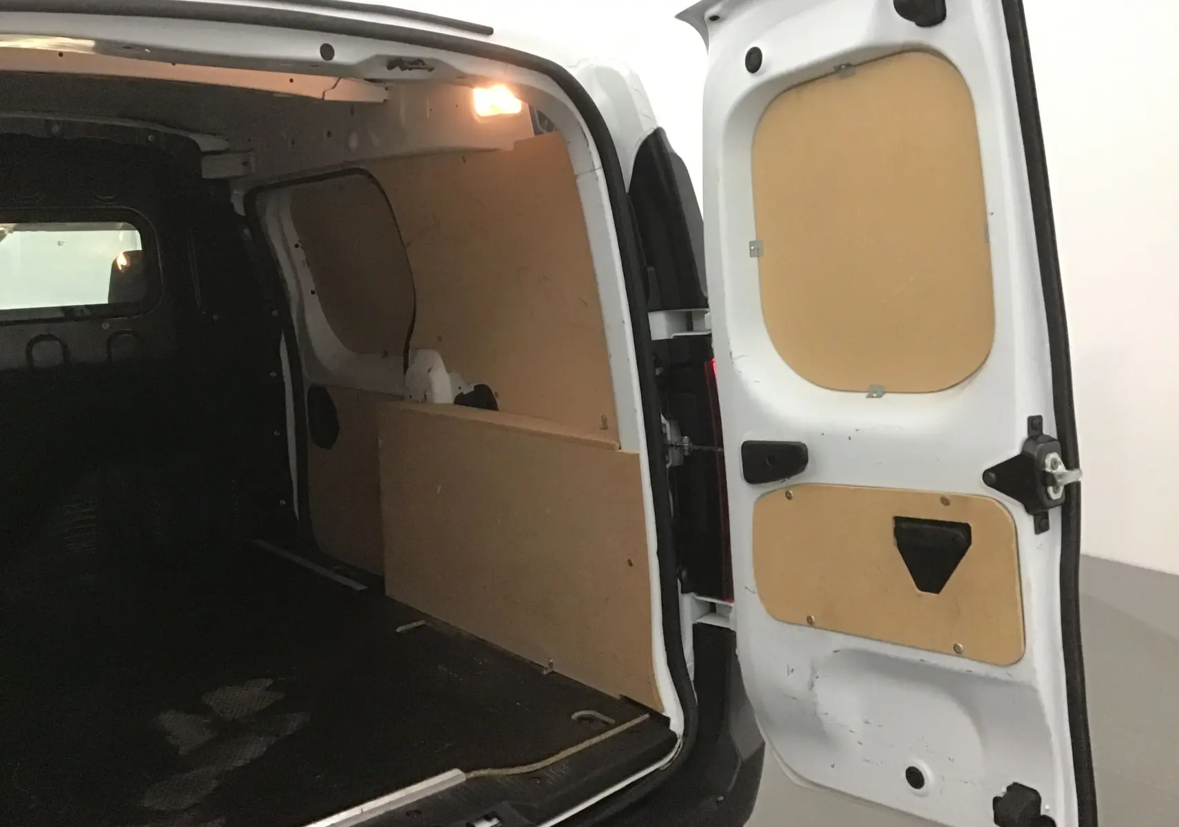Vue intérieure arrière du Renault Express Van blanc 2023, montrant l'espace de chargement avec panneaux de protection en bois.