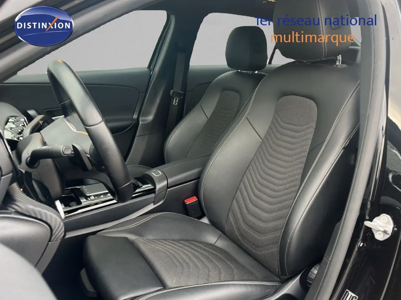 Vue intérieure côté conducteur de la Mercedes Classe A 180 Business Line 2020 avec sièges cuir noir et volant multifonction.