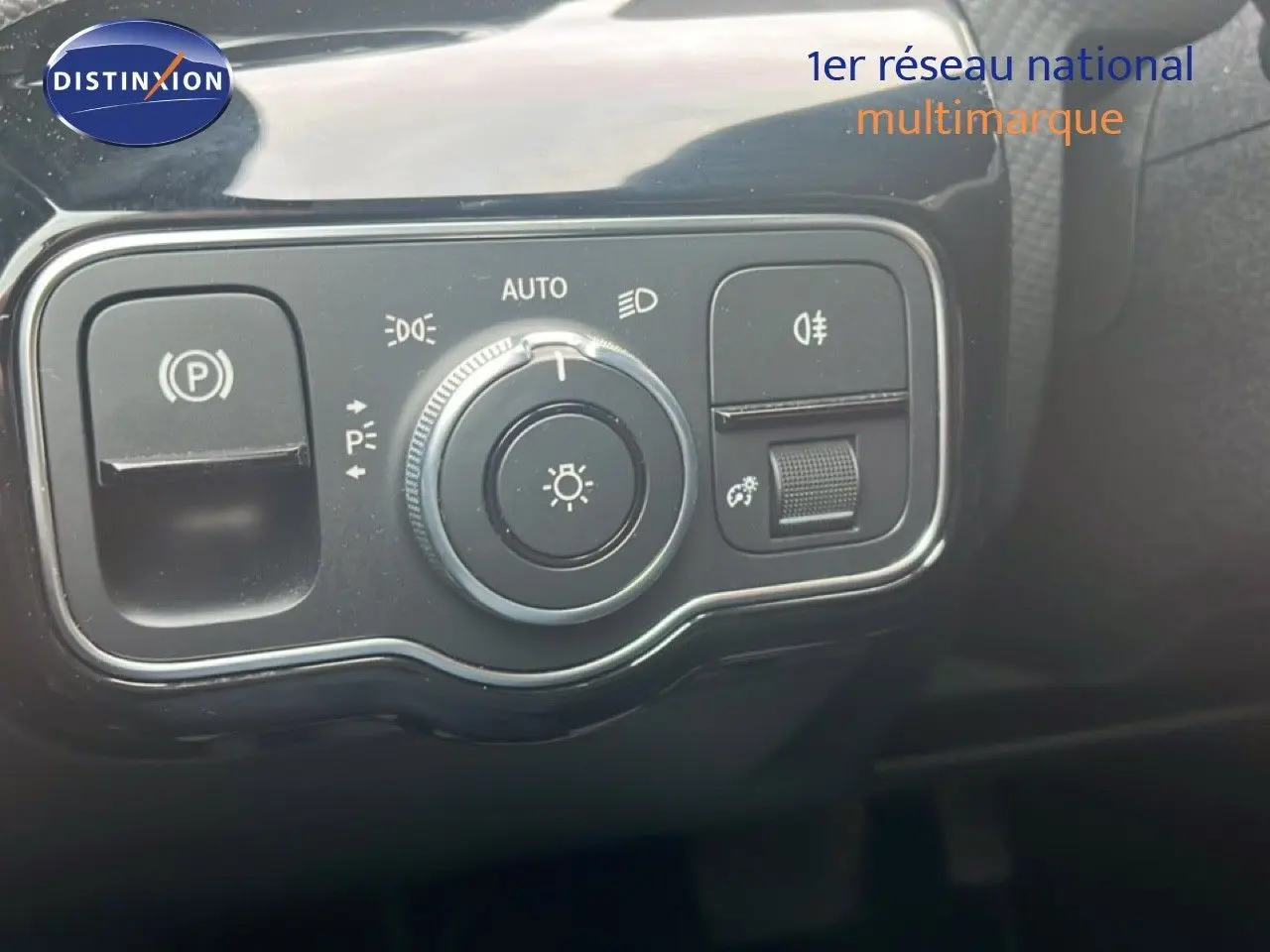 Gros plan sur les commandes d'éclairage et de frein de stationnement de la Mercedes Classe A 180 Business Line noire.