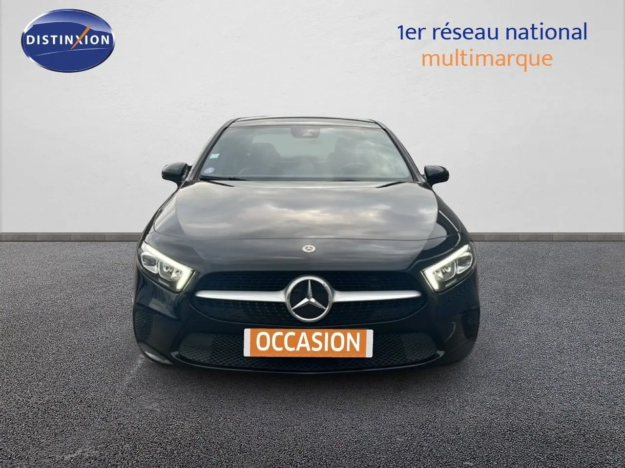 Vue frontale d'une Mercedes Classe A 180 Business Line noire Cosmos Metal avec phares LED allumés sur fond neutre.