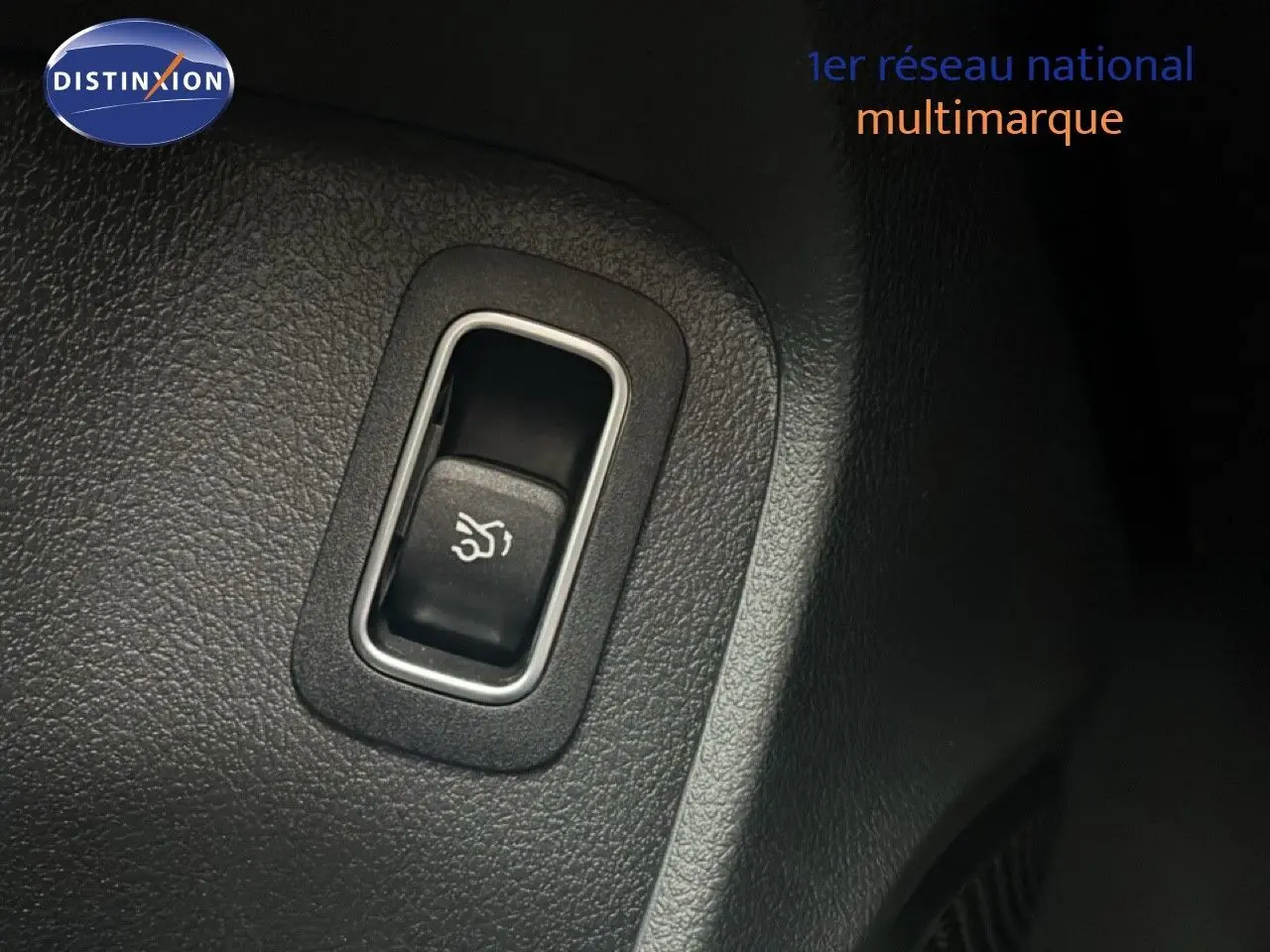 Gros plan sur le bouton d'ouverture du coffre dans l'habitacle noir d'une Mercedes Classe A 180 Business Line 2020.