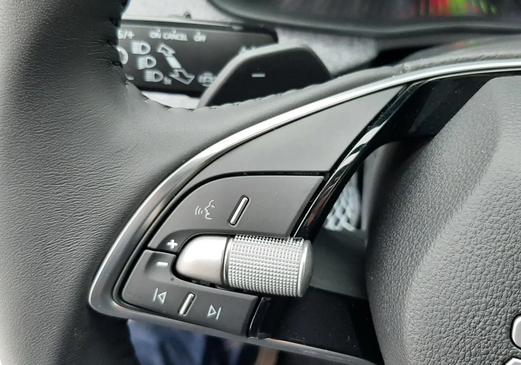 Gros plan sur les commandes gauche du volant noir du Skoda Kamiq gris graphite, avec molette et boutons multifonctions.