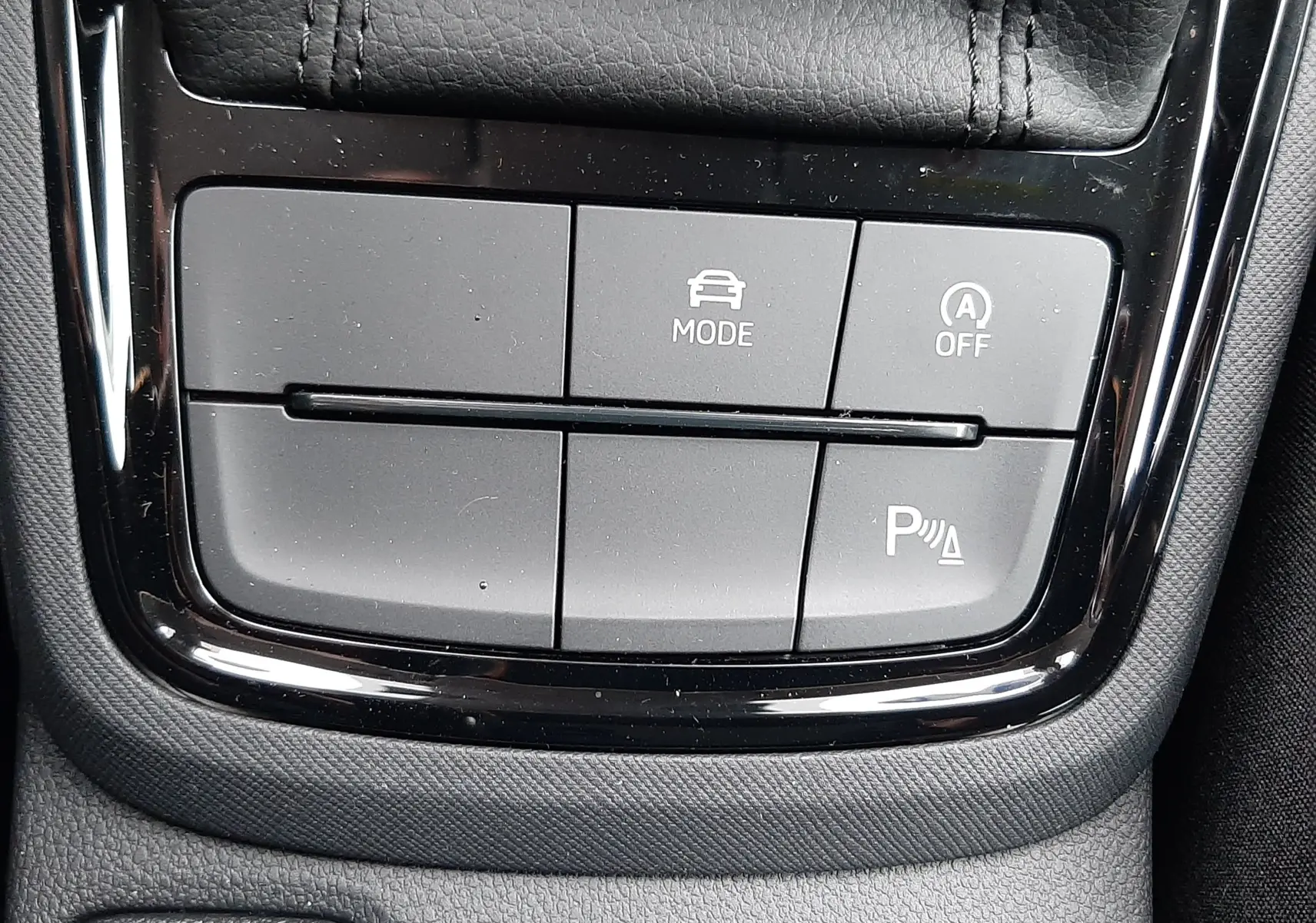 Gros plan sur les boutons de commande noirs de la console centrale du Skoda Kamiq 2025, finition tissu noir gris.