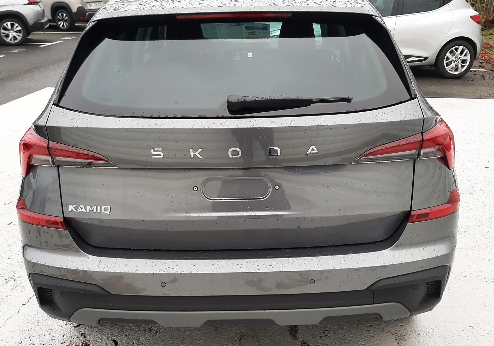 Vue arrière d'un SUV SKODA KAMIQ gris graphite métal 2025 avec feux LED et badge distinctif bien visible.