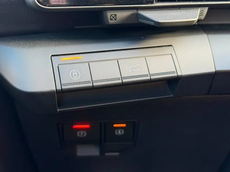 Gros plan sur les boutons de commande intérieurs du Renault Scénic E-Tech Electric blanc, avec voyants lumineux orange et rouge.