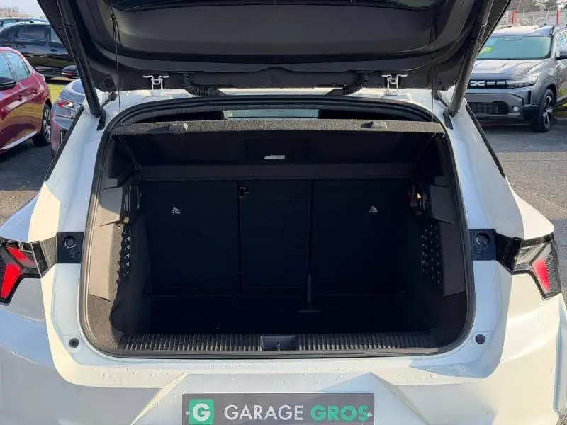 Coffre ouvert vu de l'arrière d'un Renault Scénic E-Tech électrique blanc 2025, intérieur du coffre spacieux et noir.