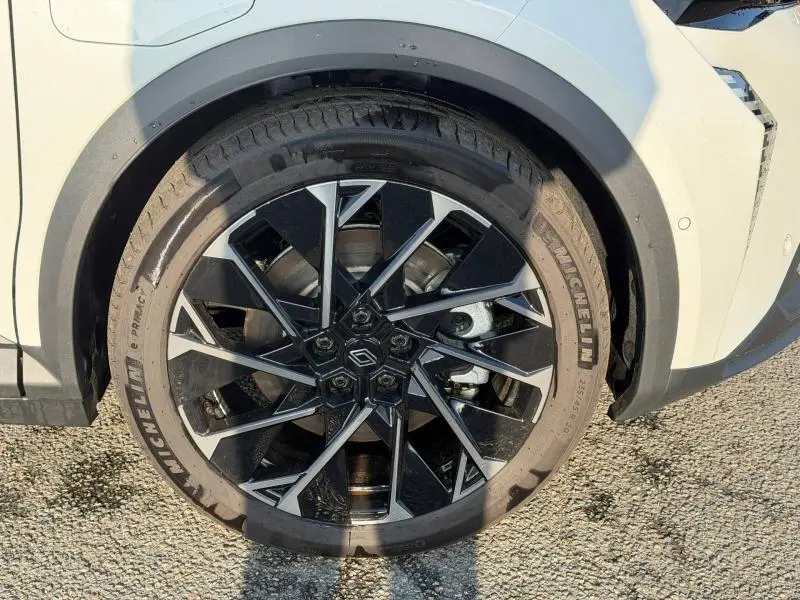 Gros plan sur la roue avant droite du Renault Scenic E-Tech blanc, jante noire et argentée au design géométrique.