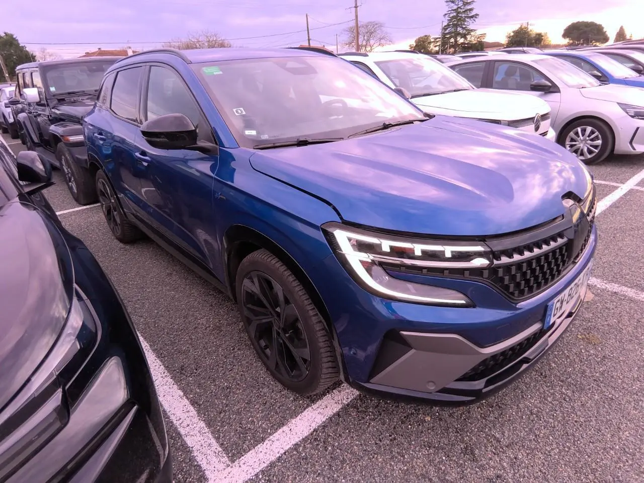 Renault Austral bleu Iron en 3/4 avant droit, avec calandre damier ice black et jantes alliage noires.