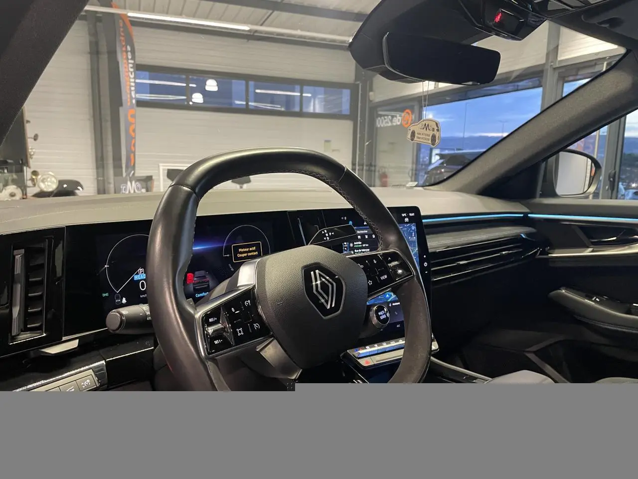 Vue intérieure côté conducteur du Renault Austral 2024, volant Alcantara et tableau de bord numérique avec éclairage bleu.