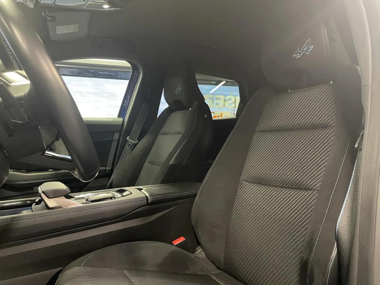 Vue intérieure côté conducteur du Renault Austral 2024, sièges noirs en tissu et Alcantara avec logo Alpine brodé.