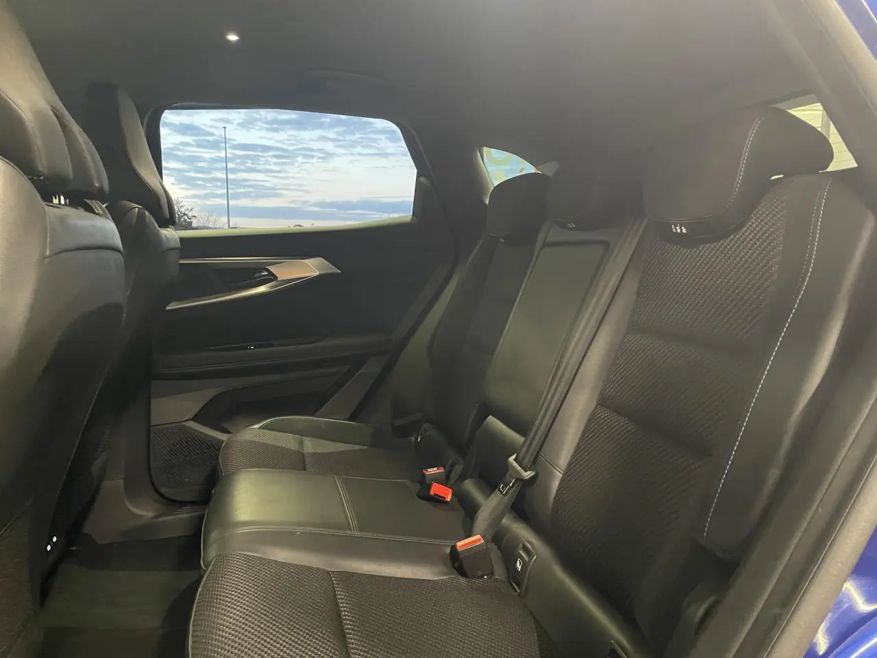 Vue intérieure arrière côté droit du Renault Austral 2024, sièges en tissu et Alcantara noirs avec surpiqûres bleues.