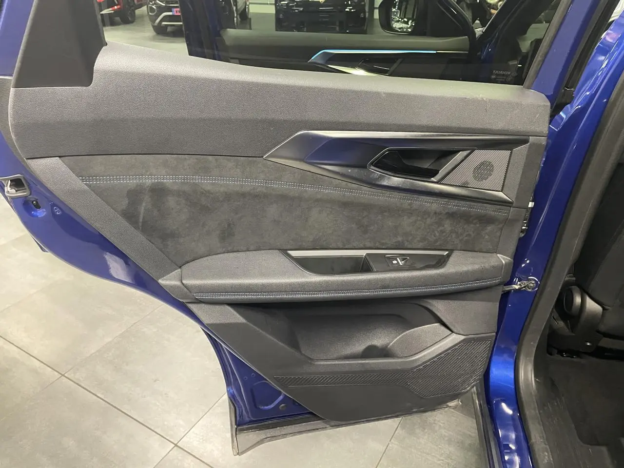 Vue intérieure côté gauche de la porte arrière bleu Iron du Renault Austral 2024 avec garniture Alcantara et surpiqûres bleues.