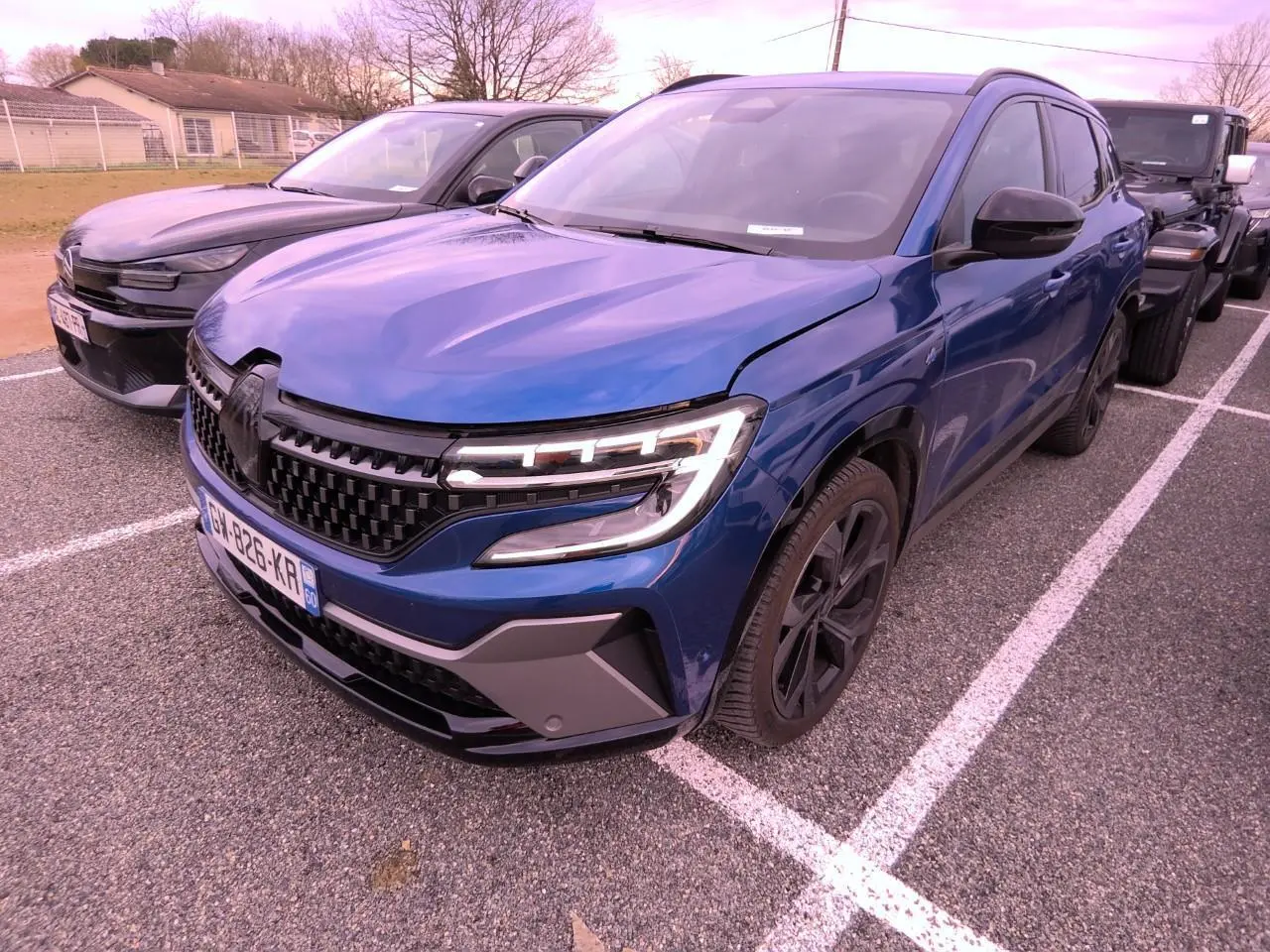 Vue 3/4 avant droite d'un Renault Austral 2024 bleu Iron avec calandre à damier et jantes alliage noires.