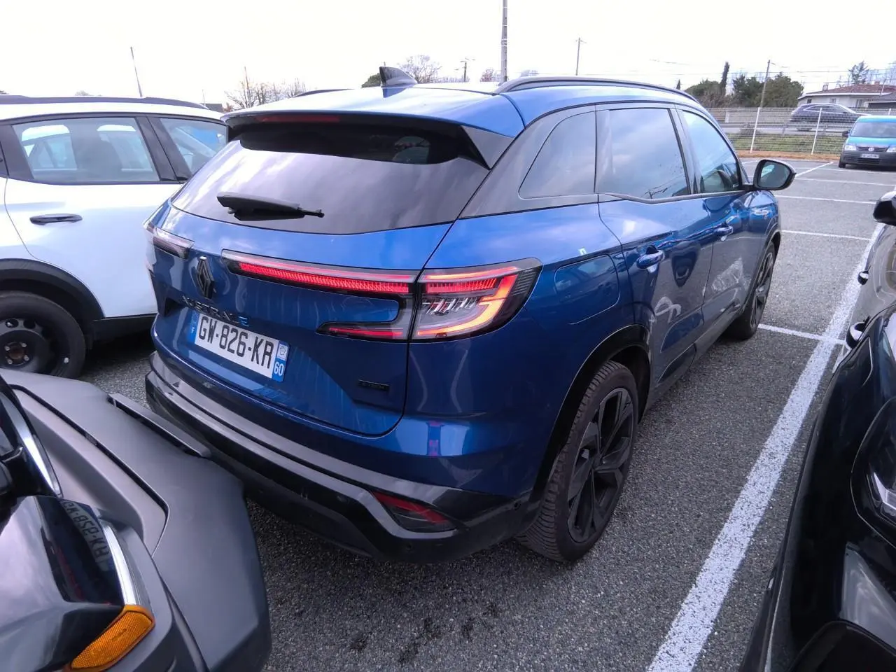 Vue 3/4 arrière droite d'un Renault Austral 2024 bleu Iron avec feux LED et jantes alliage noires.