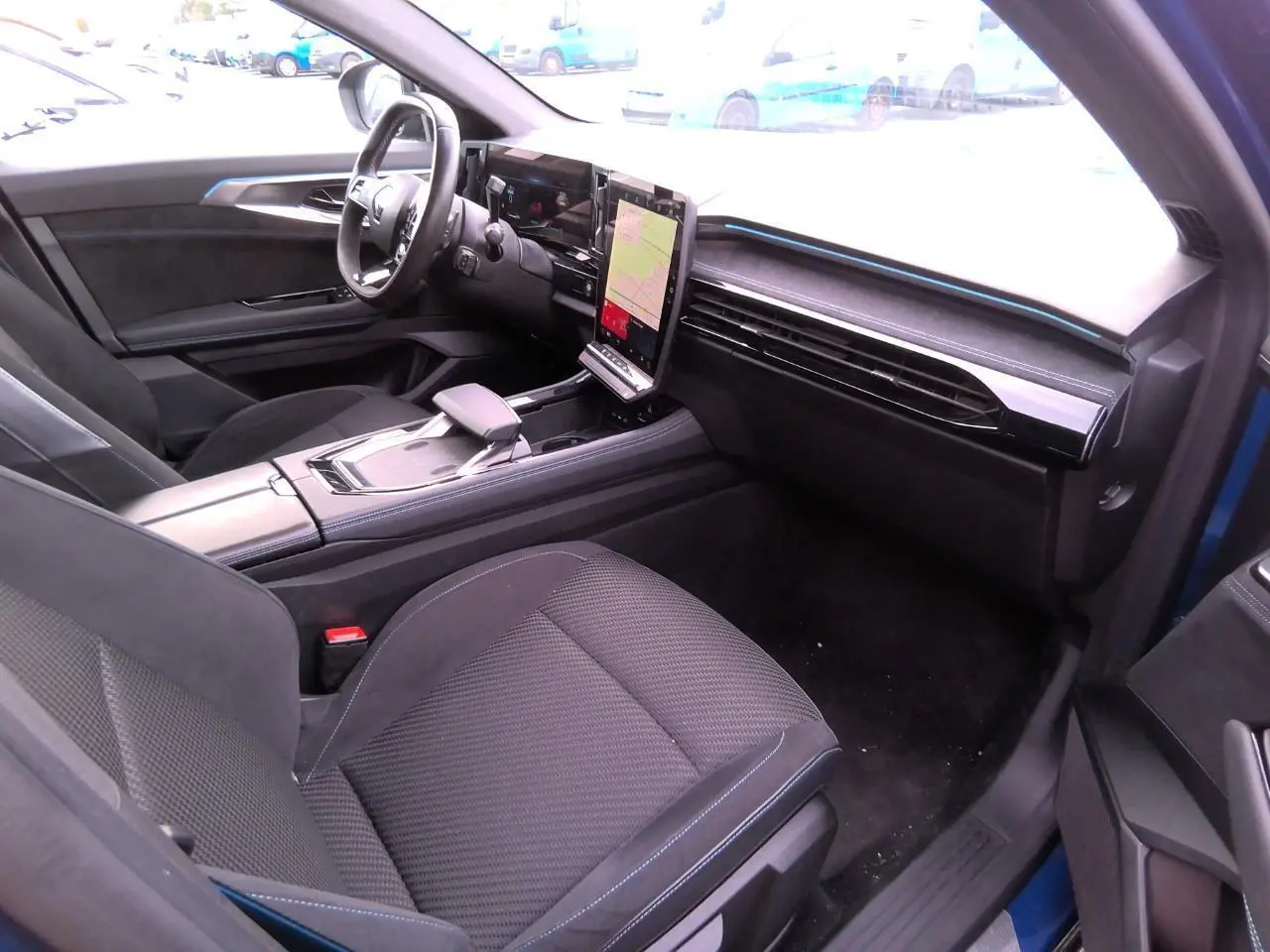 Vue intérieure côté conducteur du Renault Austral 2024 bleu, avec sellerie mixte tissu-Alcantara et écran tactile vertical.
