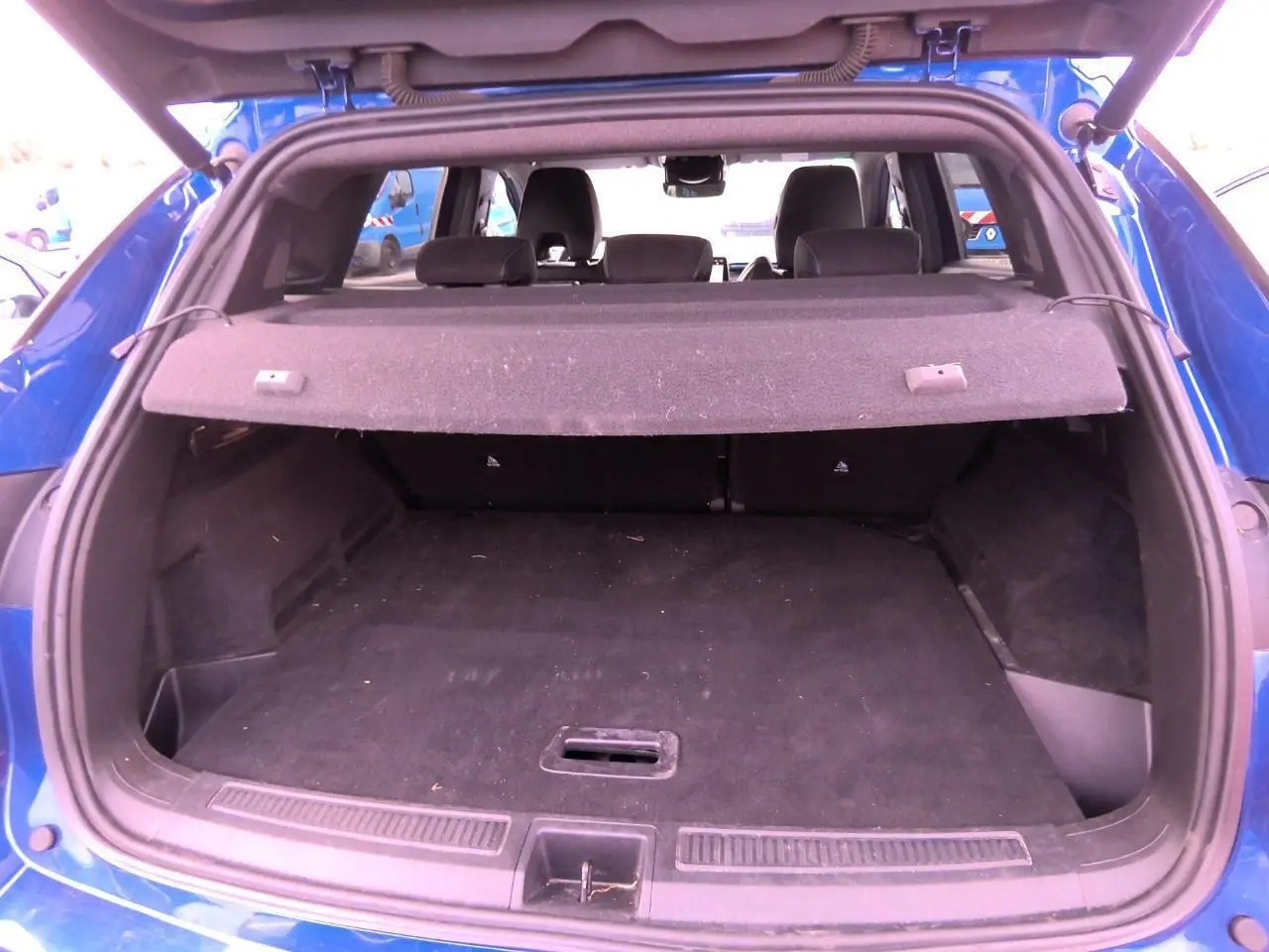 Vue arrière du coffre ouvert d'un Renault Austral 2024 en bleu Iron, montrant l'espace de chargement et la plage arrière.