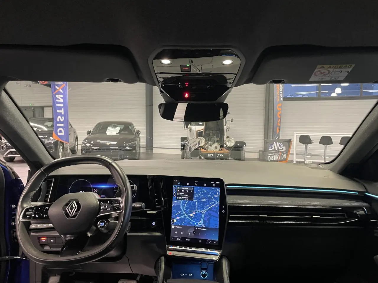 Vue intérieure avant du Renault Austral 2024 bleu, tableau de bord avec écran tactile vertical et volant multifonction.