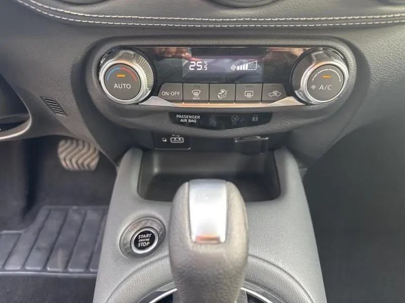 Vue rapprochée de la console centrale du Nissan Juke 2022 avec commandes climatisation, bouton start/stop et levier de vitesse.