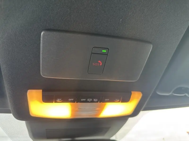 Vue intérieure en gros plan du plafonnier avec bouton SOS illuminé sur Nissan Juke gris perle métallisé 2022.