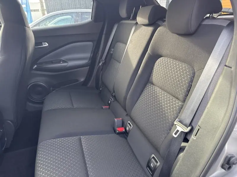 Vue latérale intérieure montrant la banquette arrière en tissu noir avec surpiqûres grises du Nissan Juke 2022.