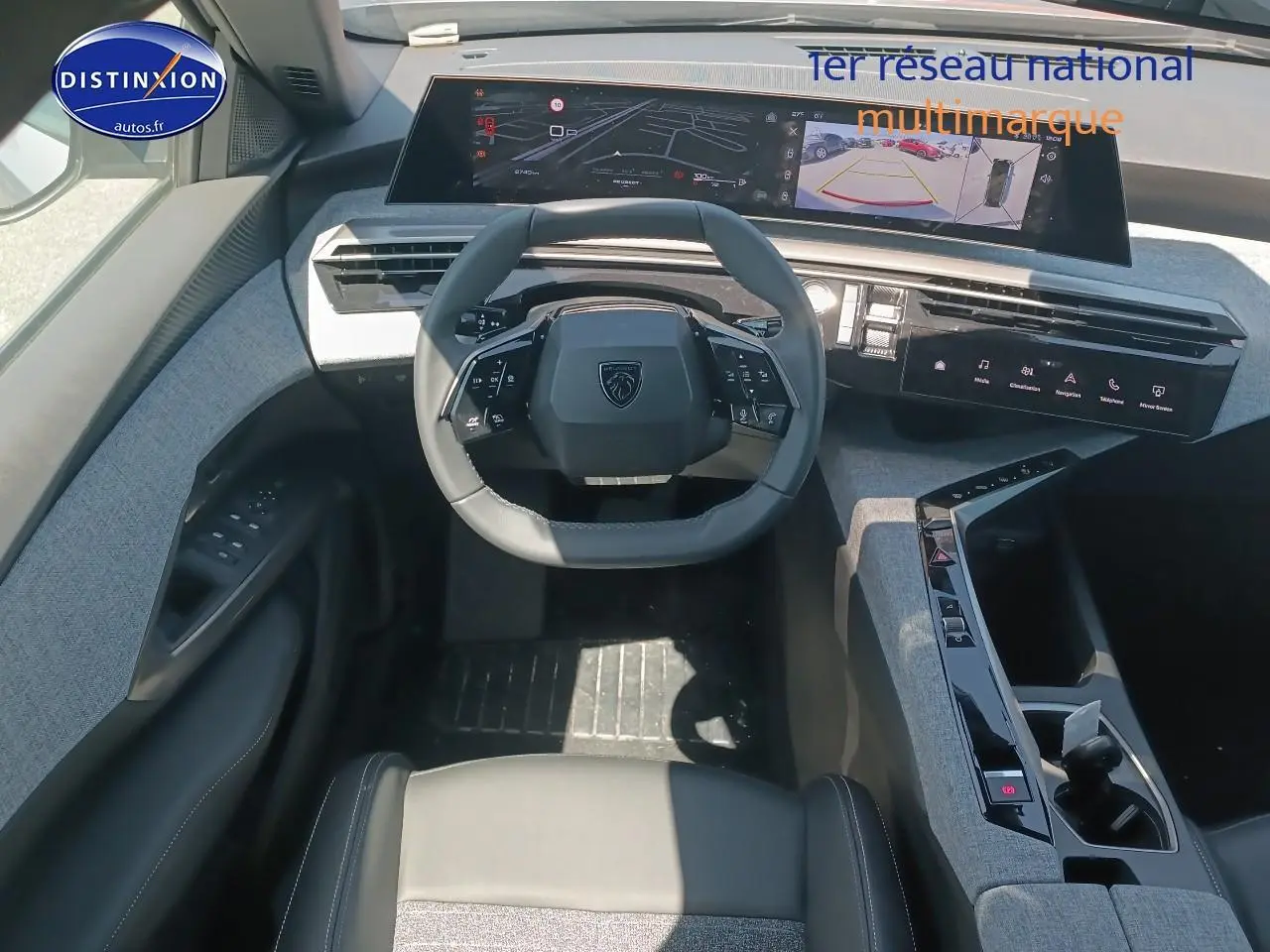 Vue intérieure frontale du poste de conduite du Peugeot 5008 Hybrid 145 allure e-dcs6 avec volant cuir et tableau de bord numérique.