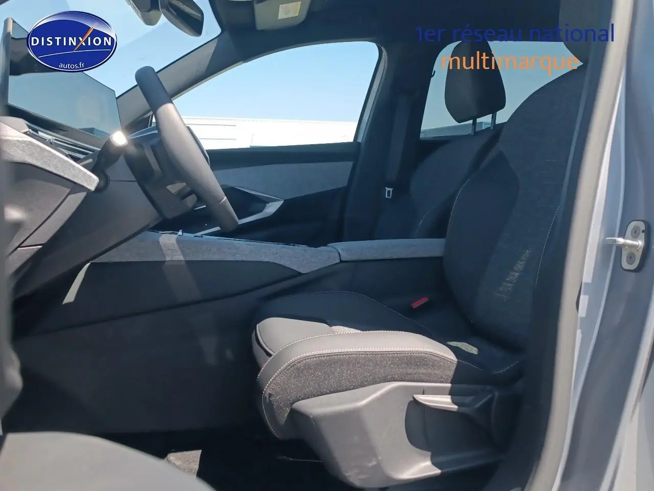 Vue intérieure côté conducteur du Peugeot 5008 gris Artense, mettant en valeur les sièges en tissu et l'accoudoir central.