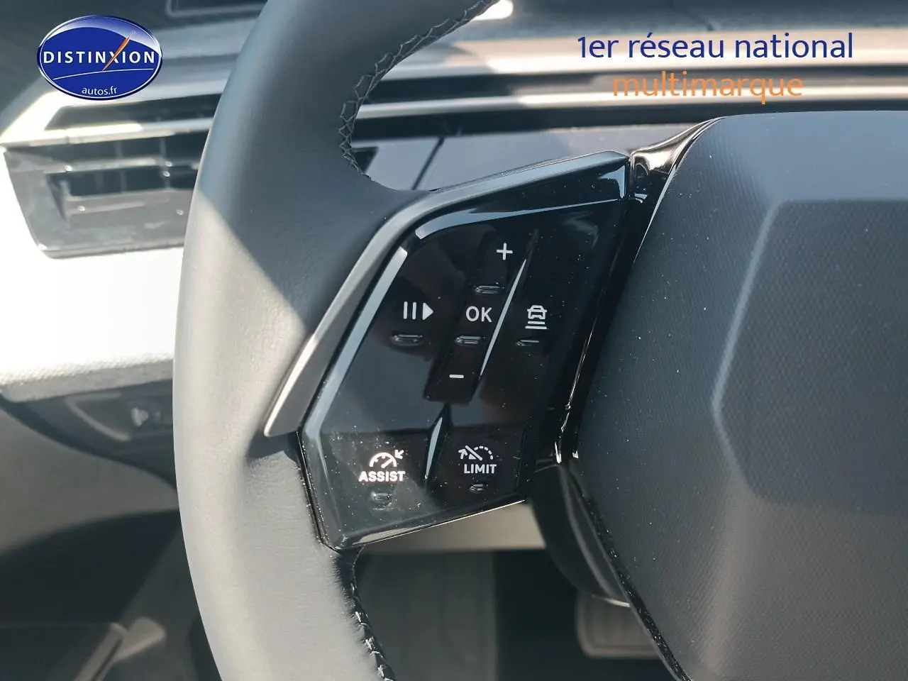 Gros plan sur le volant cuir multifonction à gauche du Peugeot 5008 gris Artense, avec commandes d'assistance visibles.
