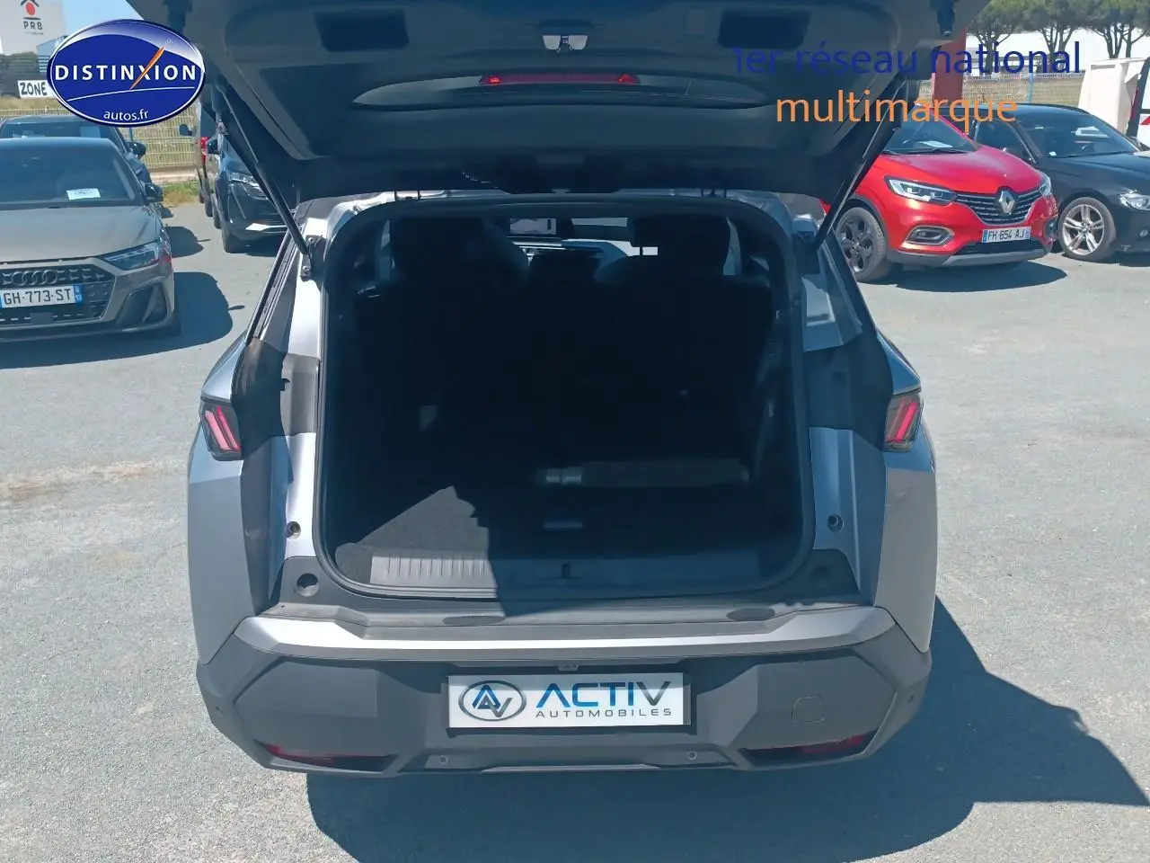 Vue arrière d’un Peugeot 5008 Hybrid 145 allure e-dcs6 gris artense avec coffre ouvert en extérieur.
