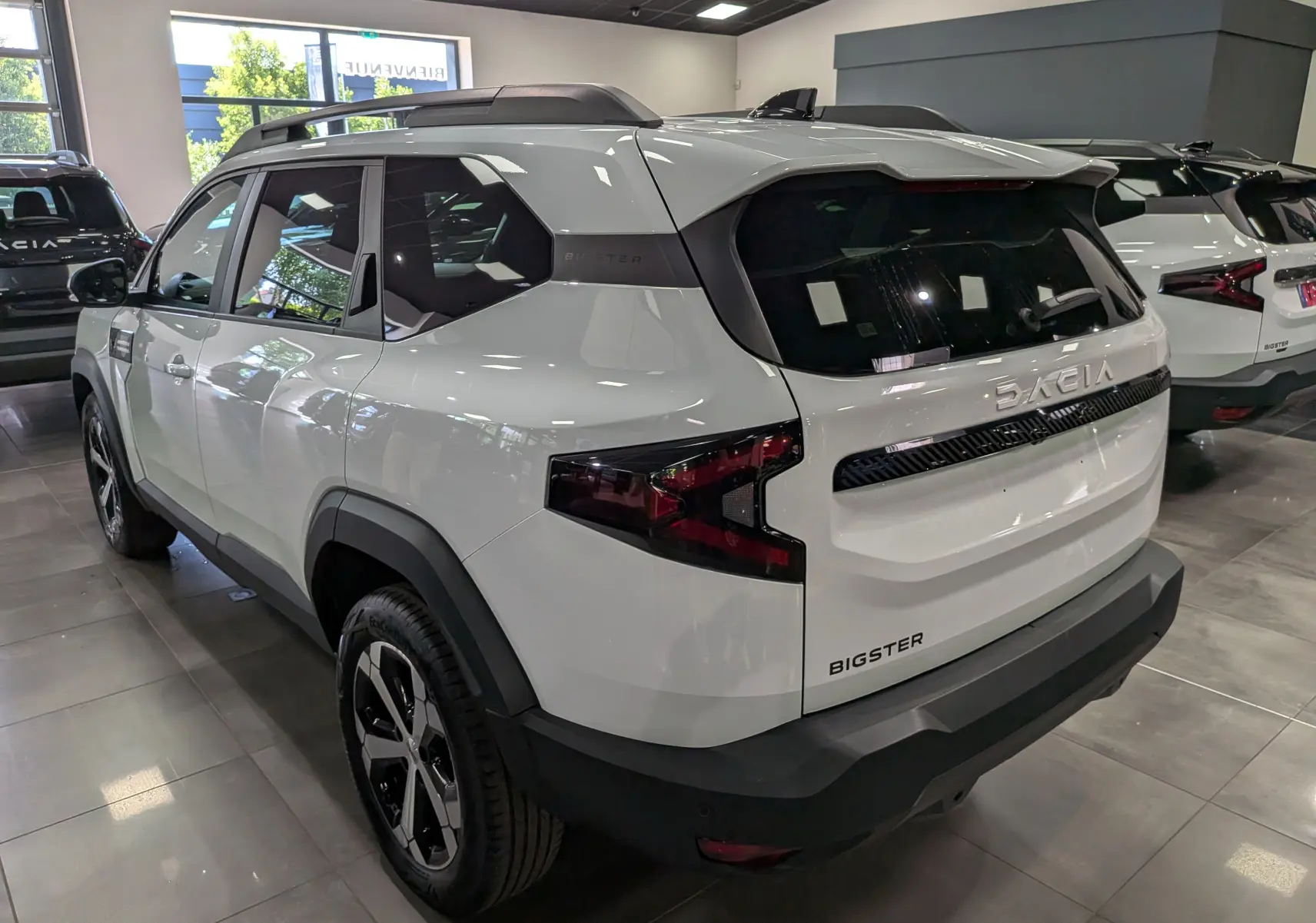 Vue 3/4 arrière droite du SUV Dacia Bigster blanc glacier, avec toit noir et feux arrière au design angulaire.