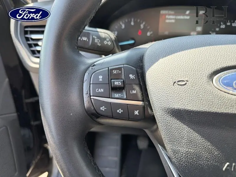 Gros plan sur le volant cuir noir de la Ford Focus 2021, avec commandes multifonctions visibles côté gauche.