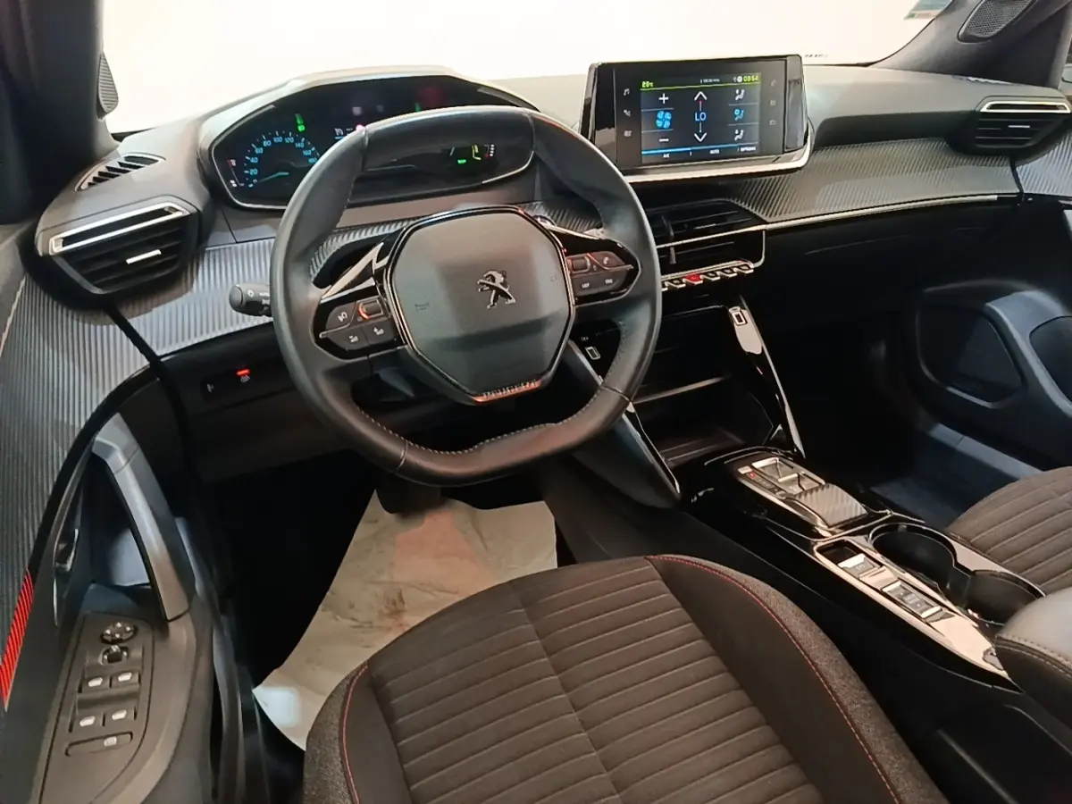 Intérieur de la Peugeot E-2008 électrique 2023 vu côté conducteur, volant cuir multifonctions et écran tactile central.