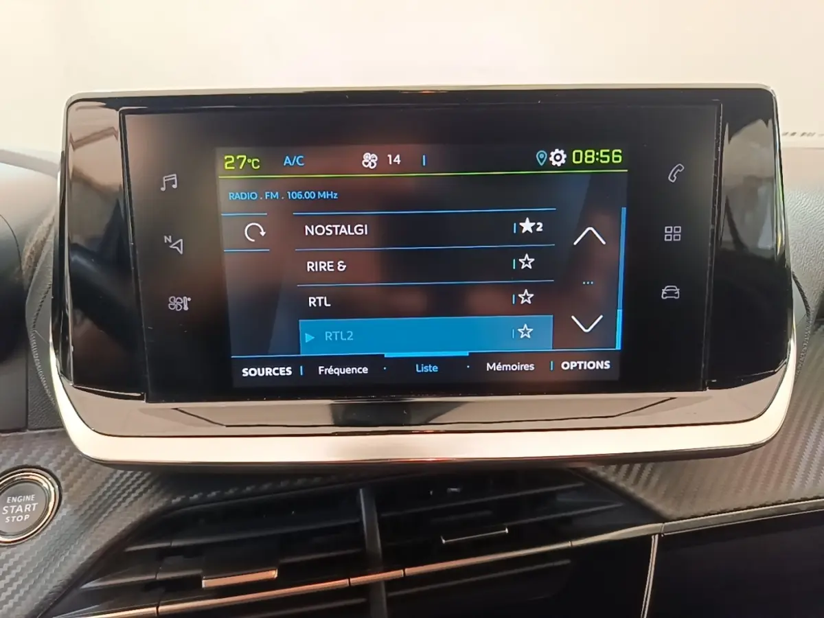 Écran tactile central allumé affichant la radio dans l’habitacle du Peugeot E-2008 électrique gris clair.