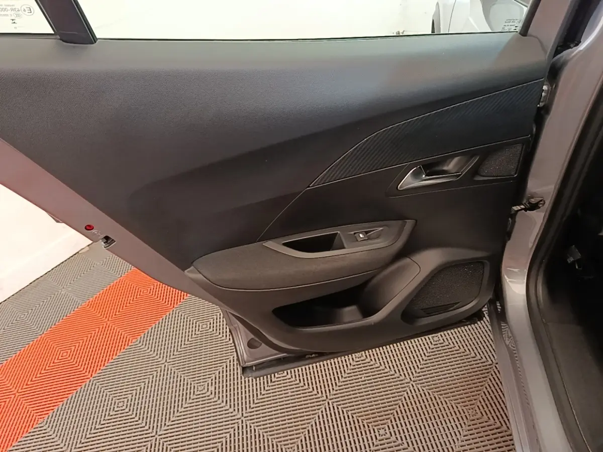 Vue intérieure de la porte arrière droite gris clair du Peugeot E-2008 électrique, avec panneau noir et commande de vitre.