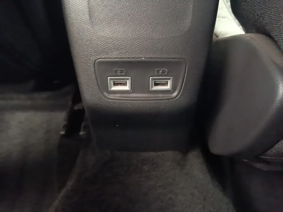 Prise double USB arrière sur console centrale noire dans l’habitacle du Peugeot E-2008 électrique gris clair.