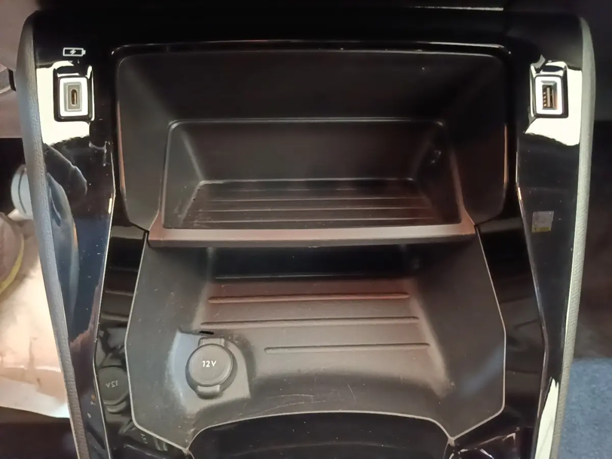 Gros plan sur la console centrale noire avec prise 12V et ports USB du Peugeot E-2008 électrique 2023.
