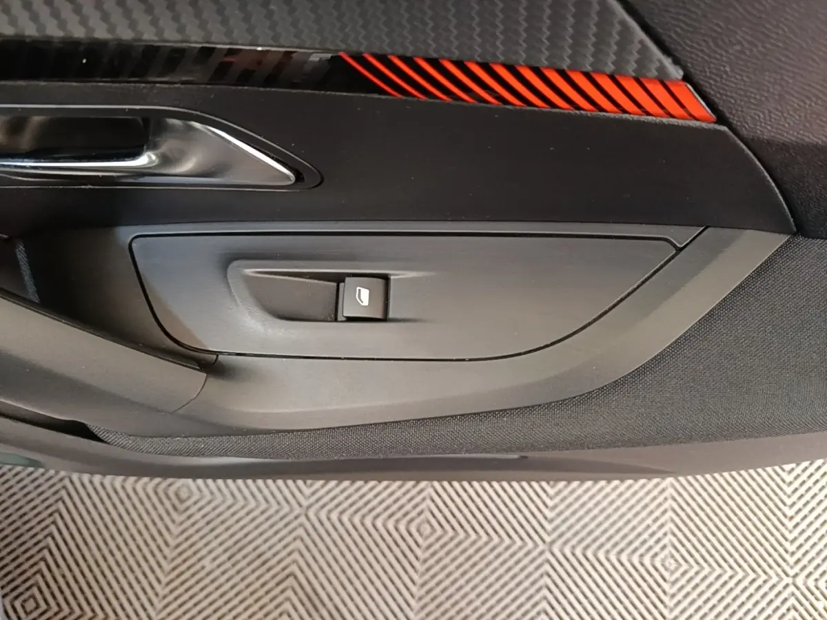 Détail de la porte intérieure côté conducteur du Peugeot E-2008 électrique gris clair, avec bouton de commande de vitre.