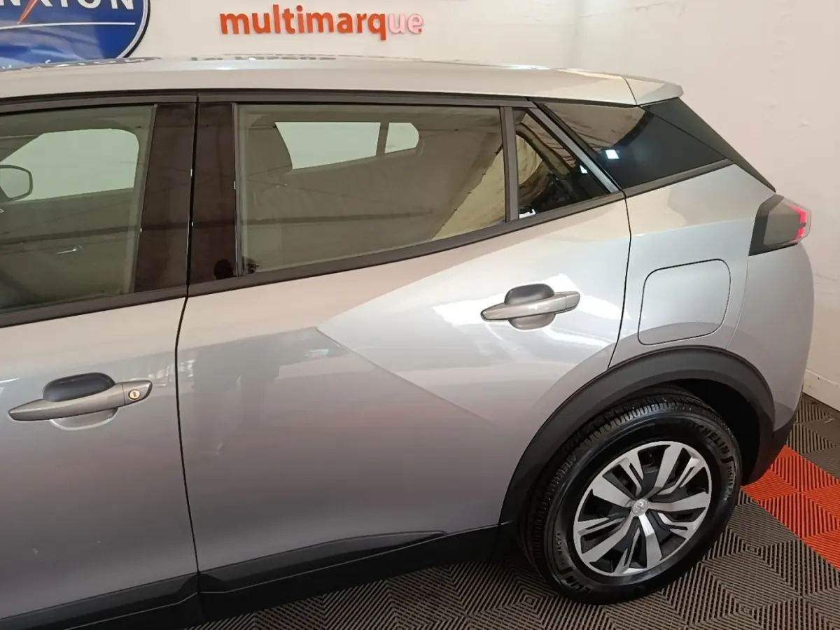 Vue latérale droite d'un Peugeot E-2008 électrique gris clair, mettant en valeur la porte arrière et la roue arrière.