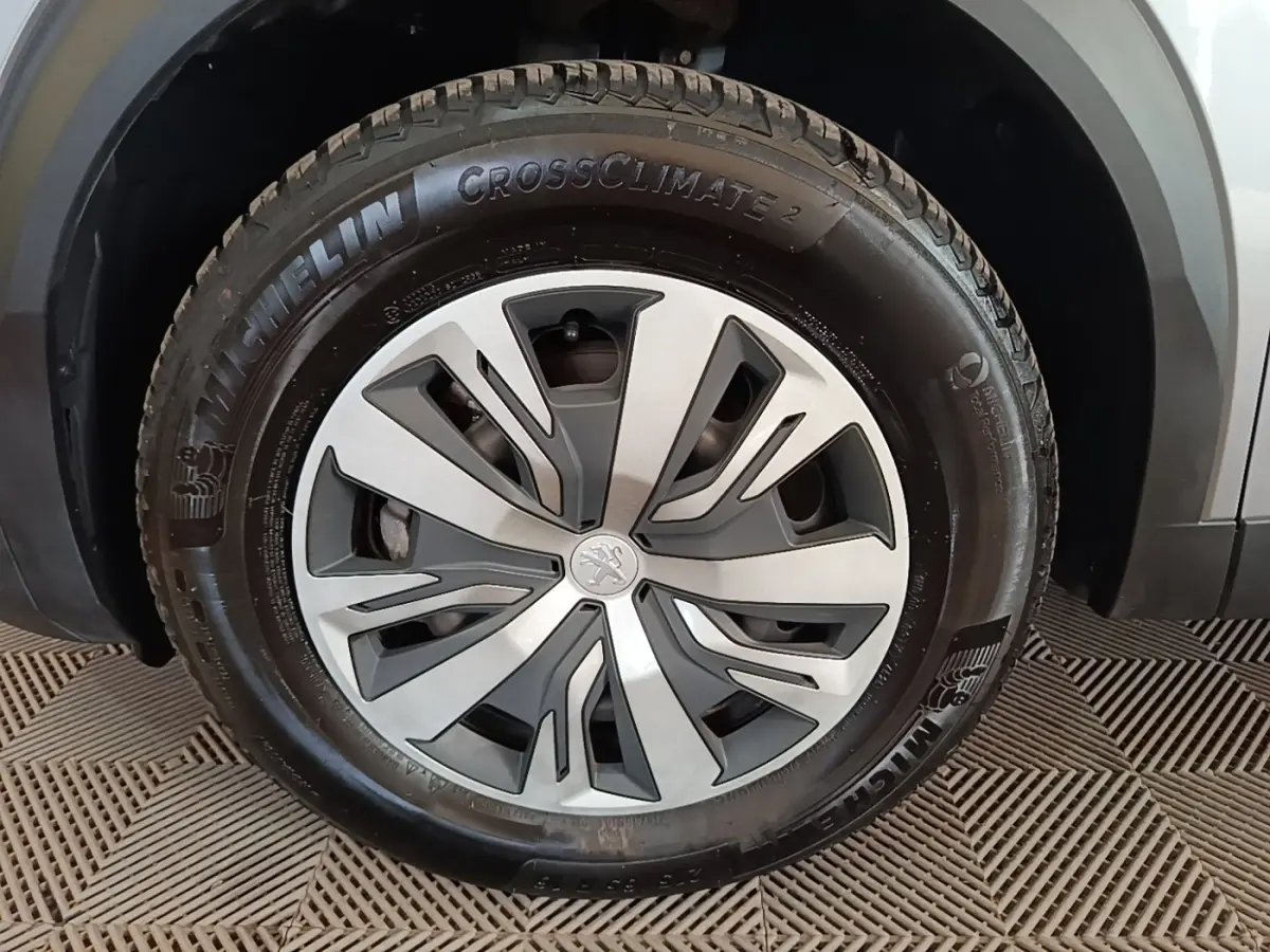 Gros plan sur la roue avant gauche gris clair du Peugeot E-2008 électrique avec jante stylisée et pneu Michelin CrossClimate 2.