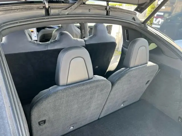 Vue intérieure arrière du Tesla Model X gris 2019 montrant les sièges rabattus et l'espace de chargement.