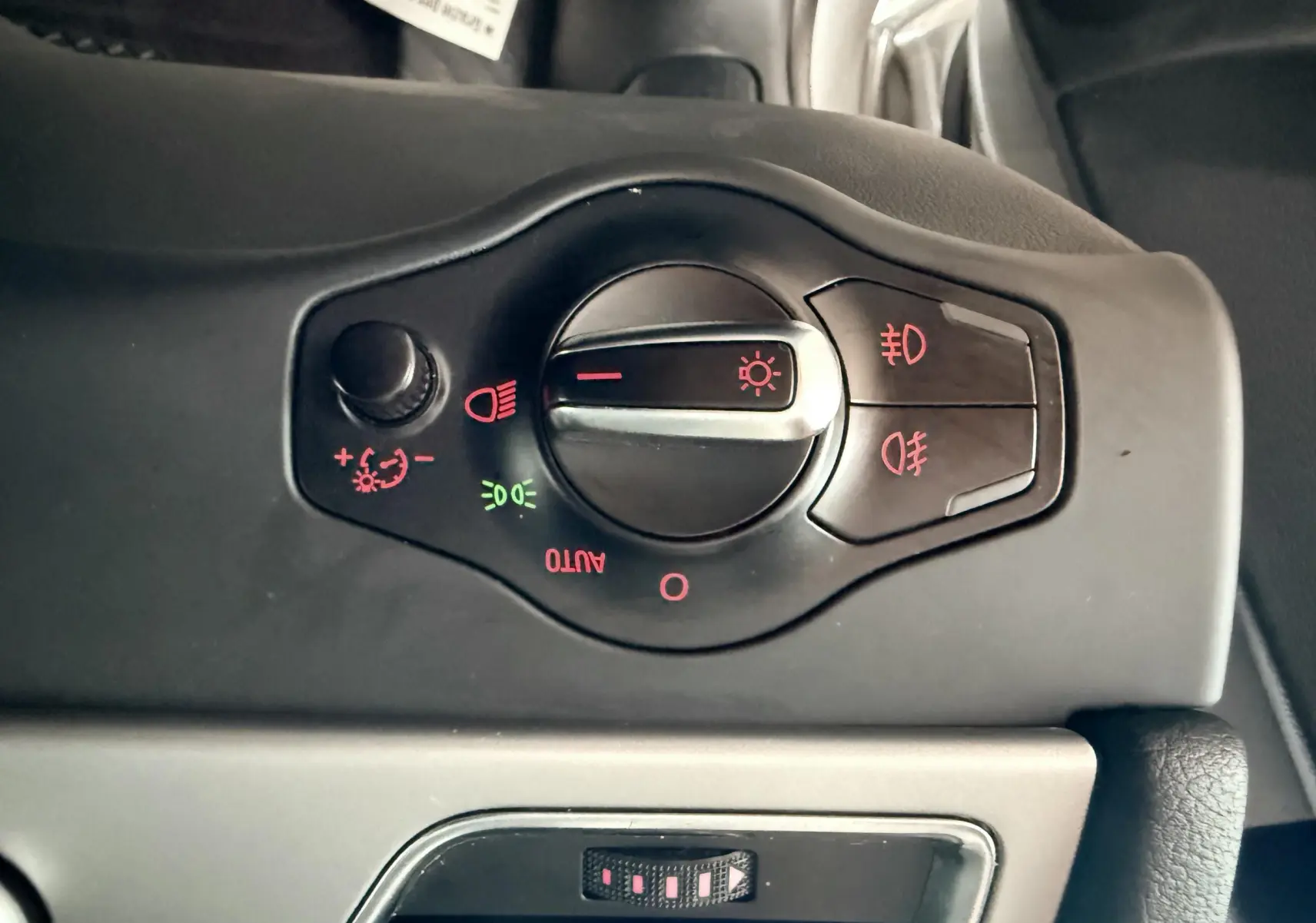 Gros plan sur le bouton de commande des phares et feux antibrouillard dans l'habitacle noir d'une Audi A5 gris 2011