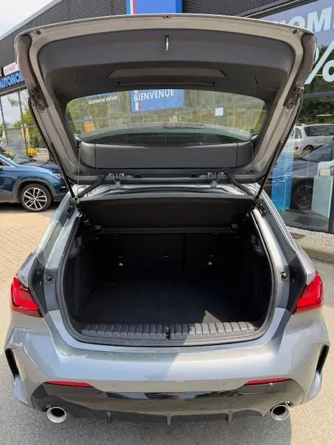 Vue arrière ouverte sur le coffre spacieux d'une BMW Série 1 118d Edition Sport gris foncé 2024, feux arrière LED visibles.