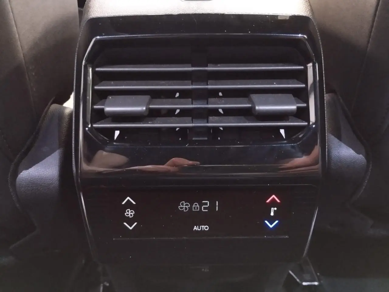 Vue rapprochée de la commande de climatisation arrière noire brillante du Peugeot 5008 Bleu Ingaro, affichant 21°C en mode auto.