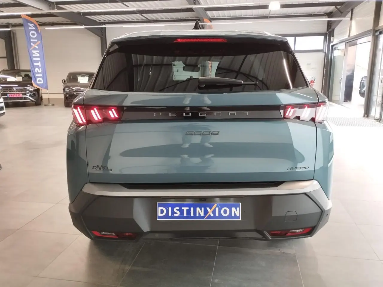 Vue arrière d'un Peugeot 5008 bleu Ingaro avec feux arrière LED 3 griffes et bandeau noir laqué portant le logo Peugeot.