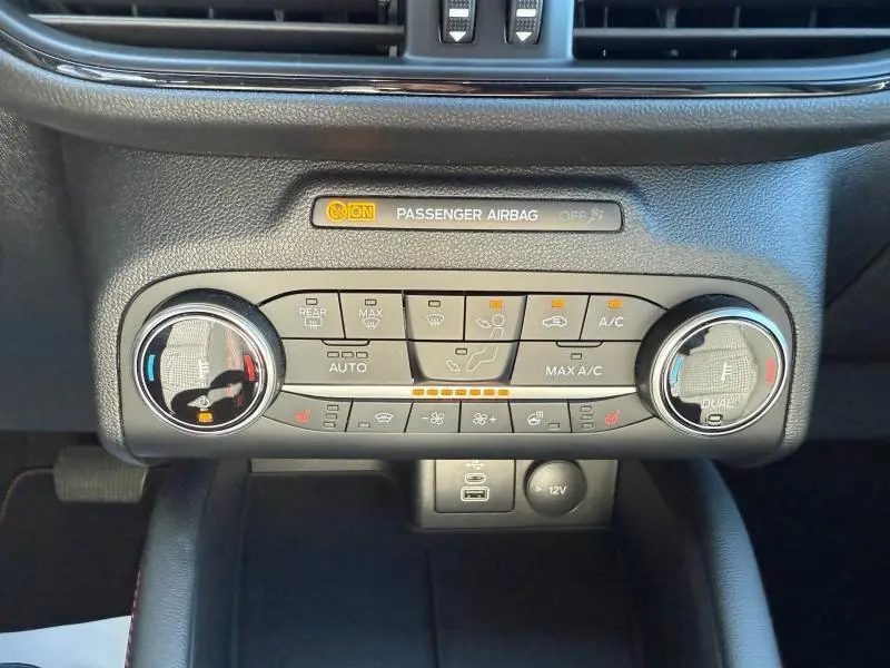 Vue rapprochée de la console centrale du Ford Kuga 2024 bleu, montrant les commandes de climatisation automatique bi-zone et ports USB.