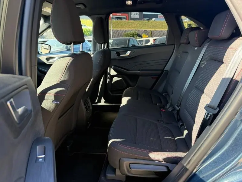 Vue intérieure côté droit montrant les sièges arrière noirs avec surpiqûres rouges du Ford Kuga bleu 2024.