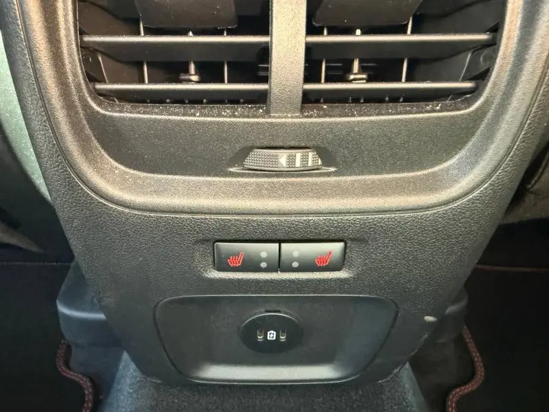 Gros plan sur la console arrière noire du Ford Kuga bleu 2024, avec aérateurs, commandes de sièges chauffants et prise USB.