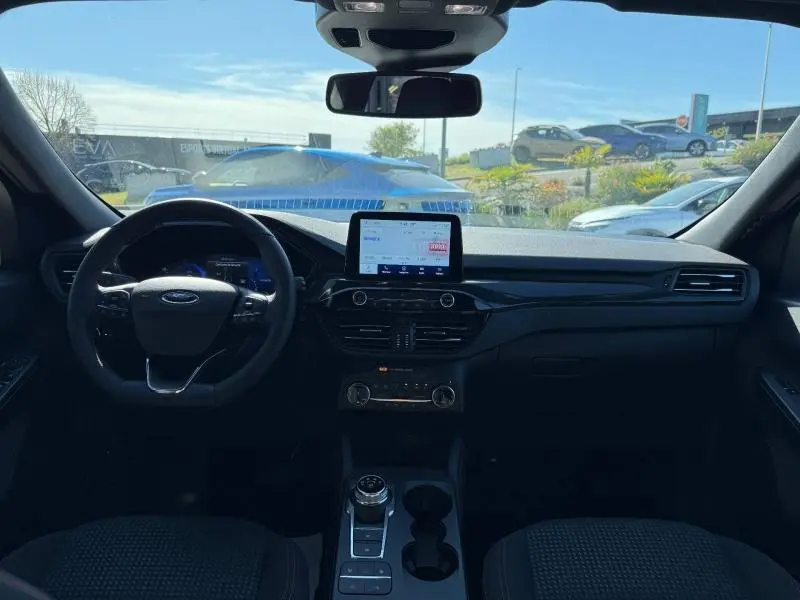 Vue intérieure avant du Ford Kuga 2.0 EcoBlue 2024 avec tableau de bord noir et écran tactile central lumineux.